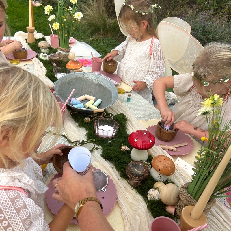 Van bovenaf: de kinderen vullen hun eigen fairy jar aan de lange tafel