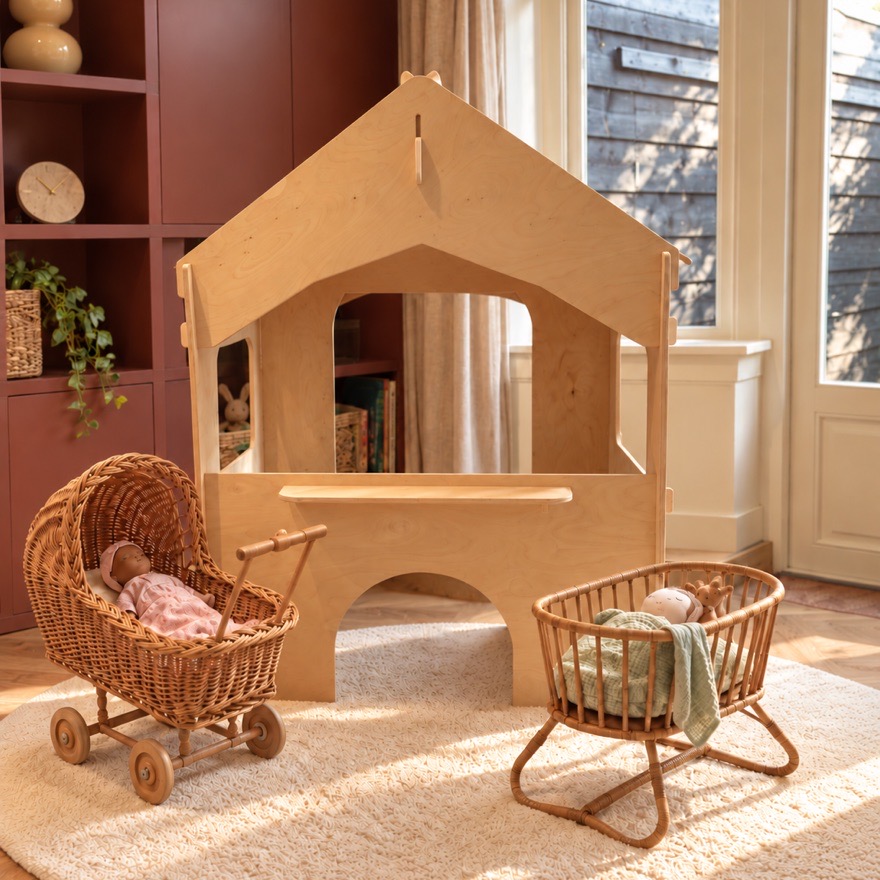 Houten speelhuisje met een rieten poppenwagen en een wiegje ervoor