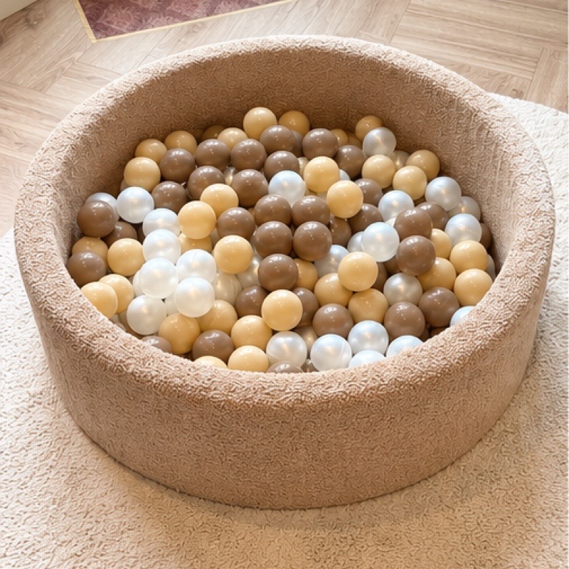 De ballenbak met houten en parelmoeren ballen, op een zacht rond kleed