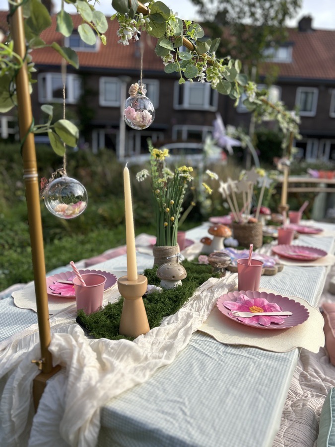 Gedekte picknicktafel in de avondzon, met kaarsen, glazen bollen en bloemen