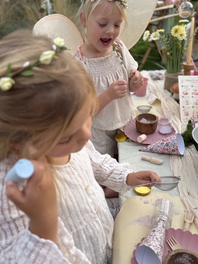 Twee kinderen aan tafel, eentje kijkt verrast naar wat ze net gemaakt heeft