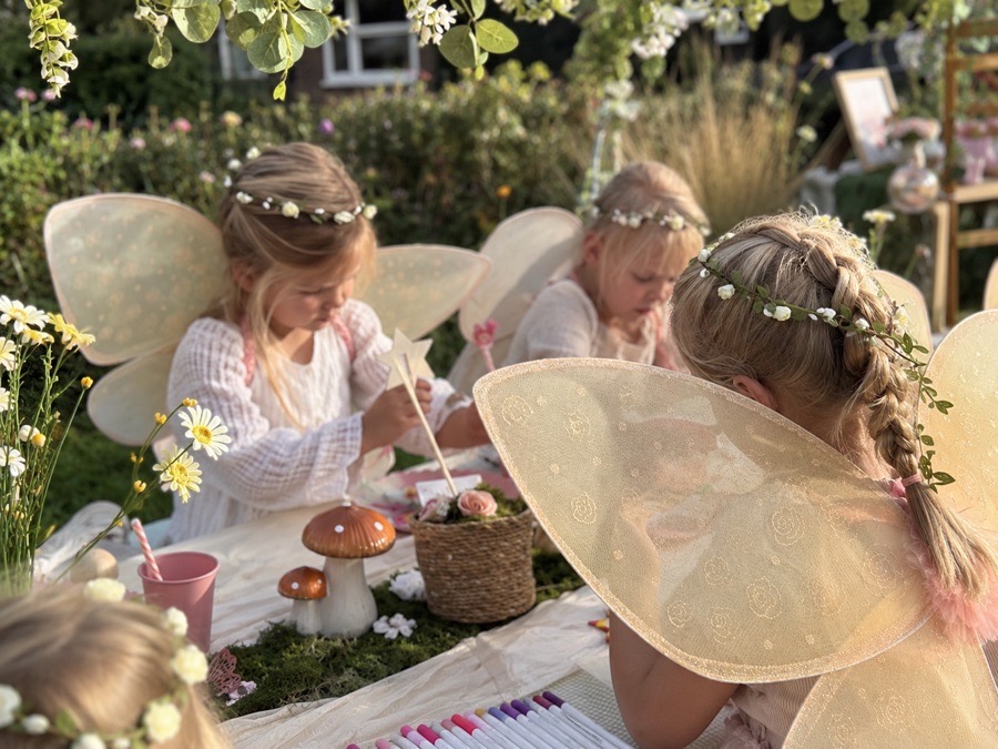 Drie feeën aan de tafel, verdiept in hun knutselwerk in de avondzon