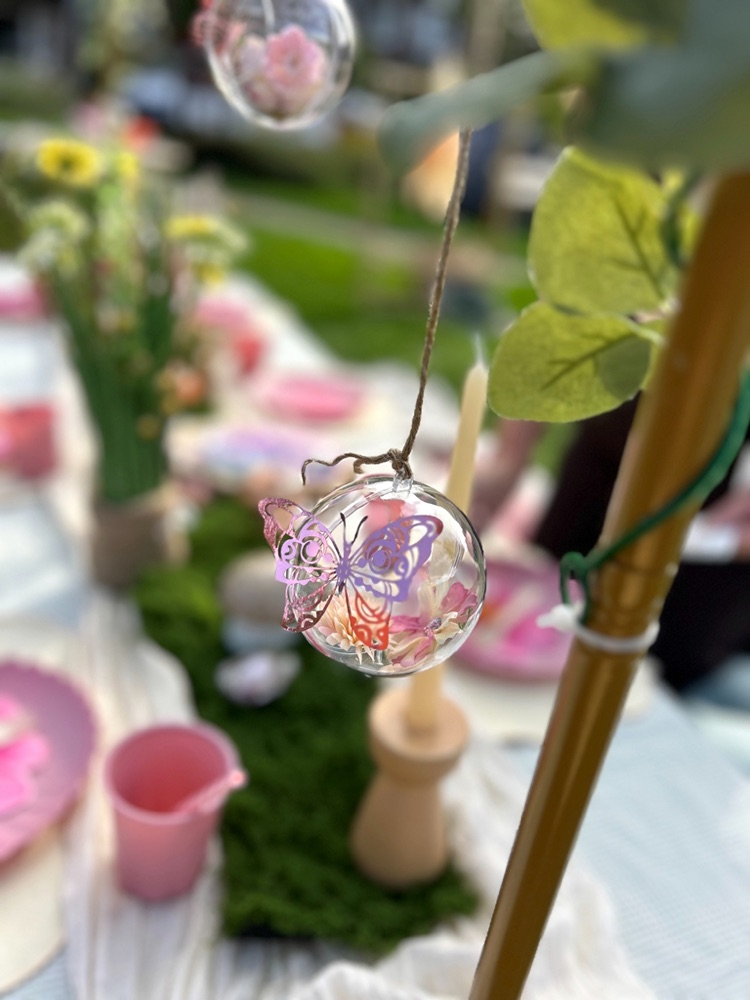 Een glazen bol met een vlinder erin, aan een lint boven de tafel