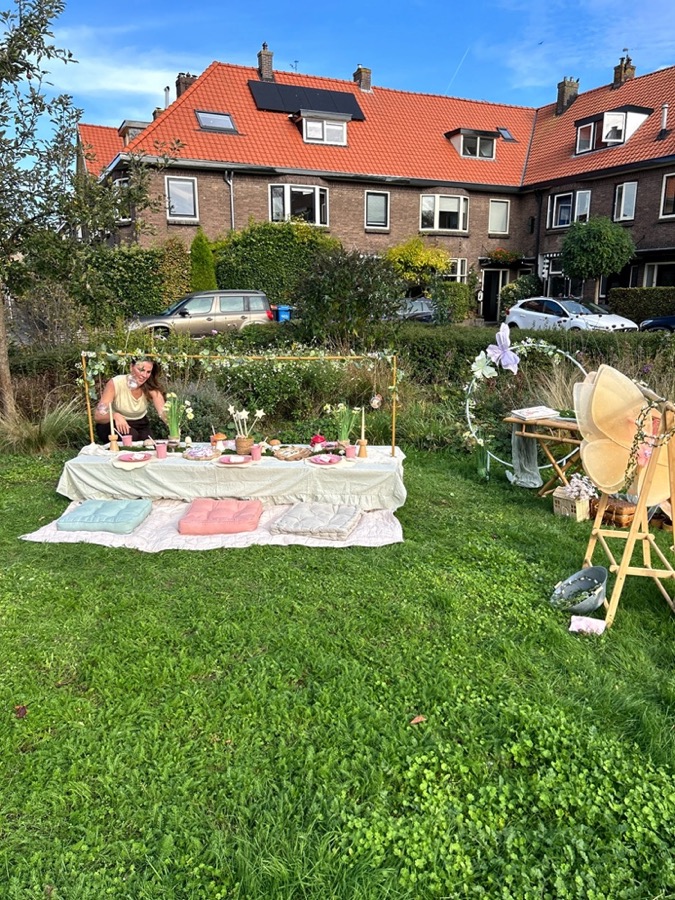 De hele setting in de tuin: picknicktafel, kussens, bloemenboog en het kledingrek