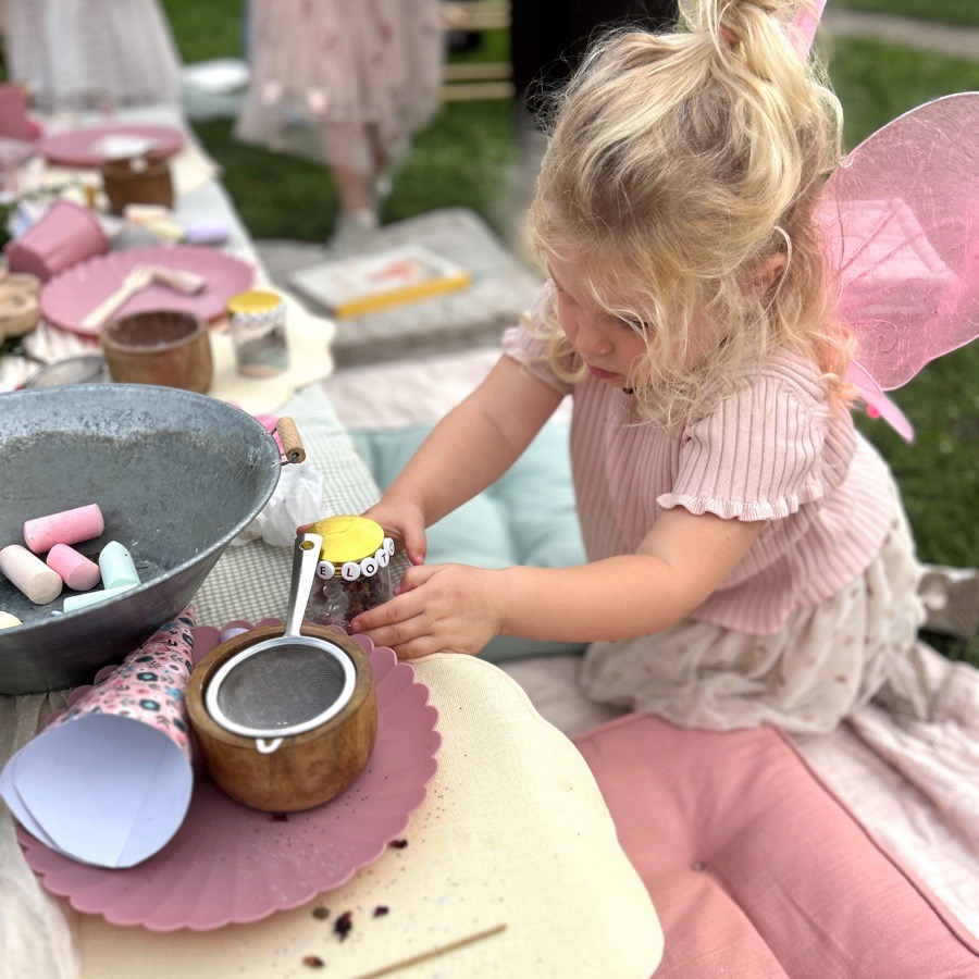 Meisje schept laagje voor laagje haar eigen fairy jar vol